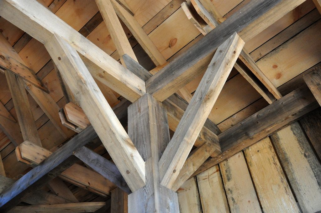 A close-up view of intricate wooden joinery in a carpentry project, showcasing the craftsmanship involved in constructing a sturdy wooden frame. The beams and supports are made from natural, unfinished wood, highlighting the raw beauty and strength of the material. The precise cuts and fittings demonstrate the skill and attention to detail required in high-quality carpentry work. This image captures the essence of traditional woodworking techniques and the durability of well-crafted wooden structures.