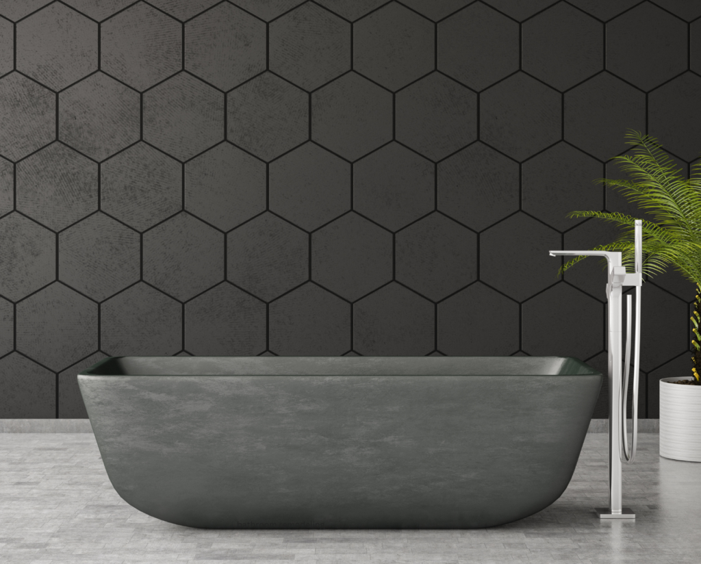 A modern bathroom featuring a sleek, dark gray bathtub with clean lines and a minimalist design, perfect for bathroom remodeling. The background consists of a stylish black hexagonal tile wall, complementing the bathtub's color. A contemporary floor-mounted faucet stands to the right of the bathtub, and a green plant adds a touch of natural color to the scene.